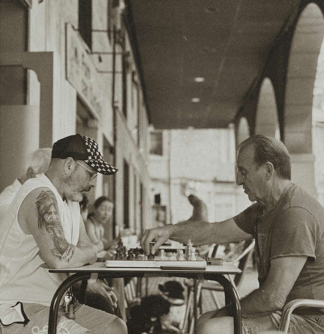 Two men playing chess at an outdoor cafe.