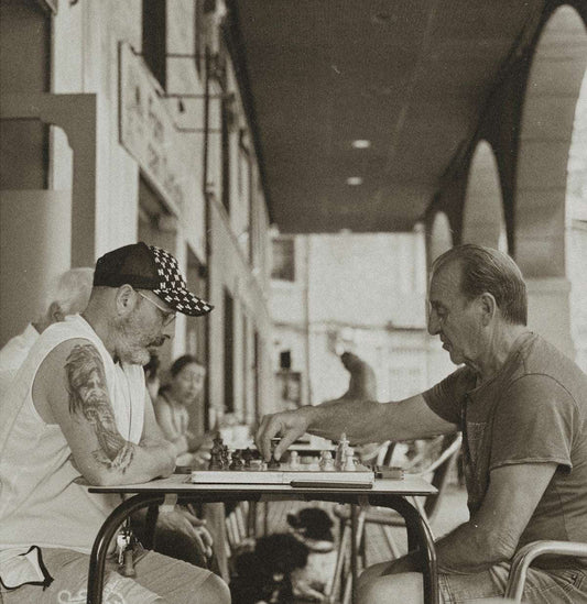 Two men playing chess at an outdoor cafe.
