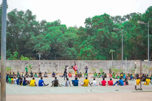 Children in colorful athletic wear watch players in community sports game